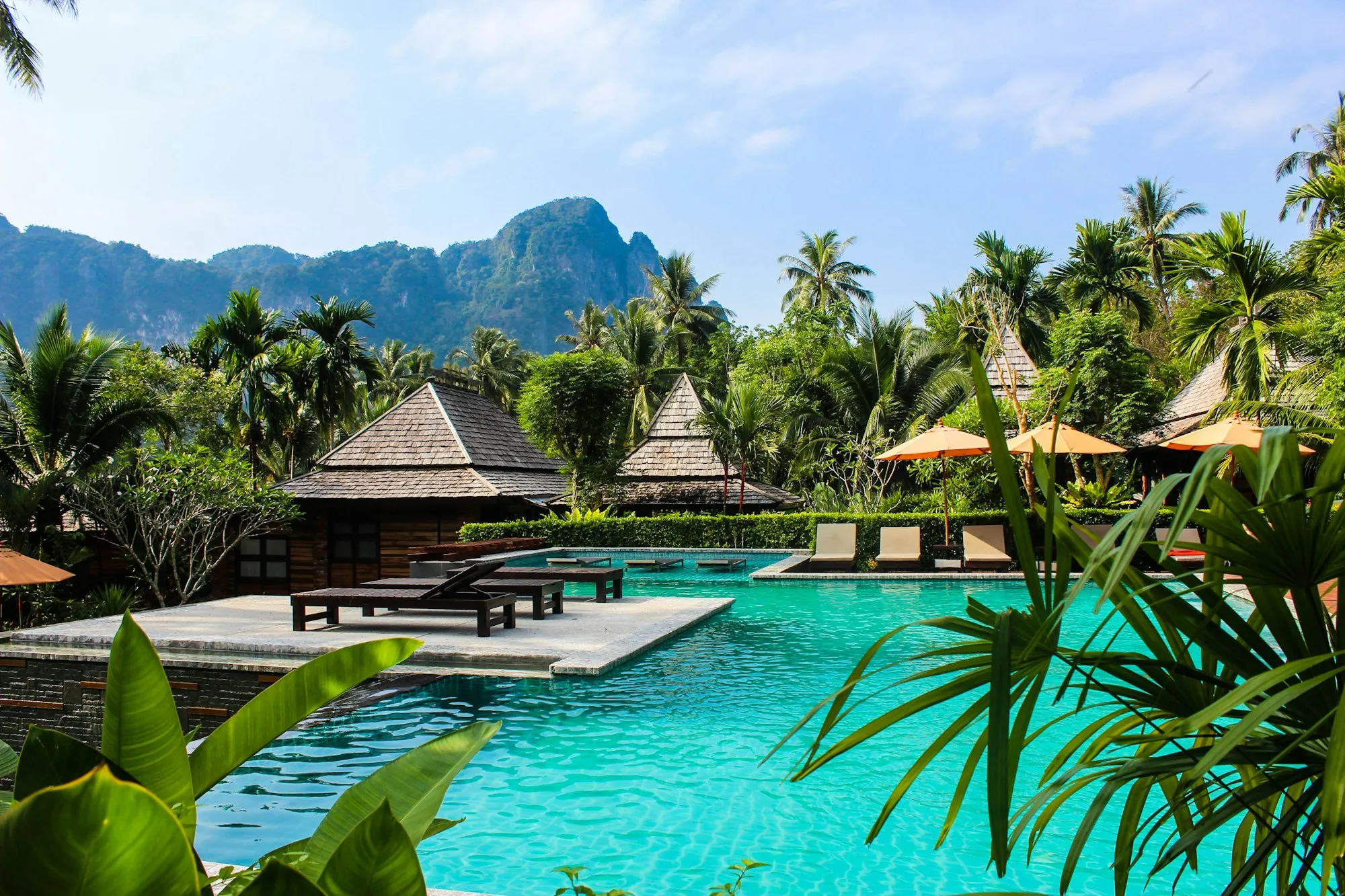 Thatched pavilions around a pool with green hills behind